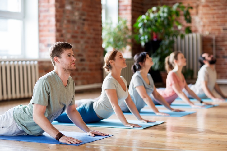 Group of people doing yoga cobra pose at studio